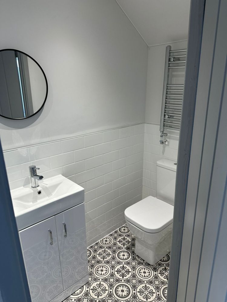 New cloakroom bathroom by Construction Edge including floor and wall tiles, toilet, sink and electric towel dryer.